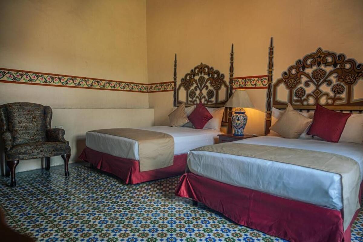 Ein Hotelzimmer mit zwei Betten, einem Sessel und einem gestreiften Boden.