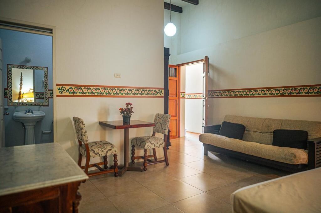 Un salon comprenant un canapé, deux fauteuils, une petite table et un miroir.