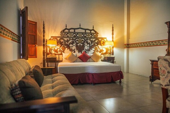 Un dormitorio con cama, sofá y dos mesitas de noche con lámparas.