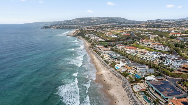 A coastal town with a beach, residential buildings, and a hilly landscape in the background. - Charming Beach condo on the Shores at Strand Beach (Dana Point)