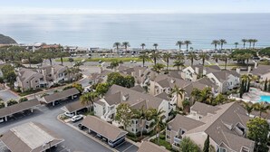 A coastal residential area with houses, a parking lot, and a view of the ocean. - Charming Beach condo on the Shores at Strand Beach (Dana Point)