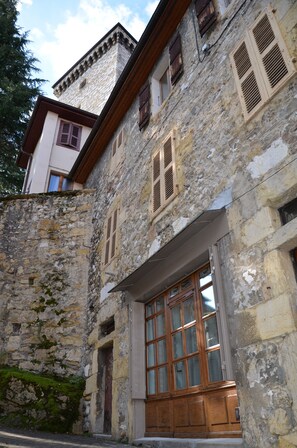 Un bâtiment en pierre avec des volets en bois, une grande porte en bois et une petite fenêtre.