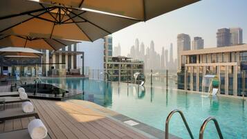 Una piscina al aire libre, camas de piscina con cargo, sombrillas