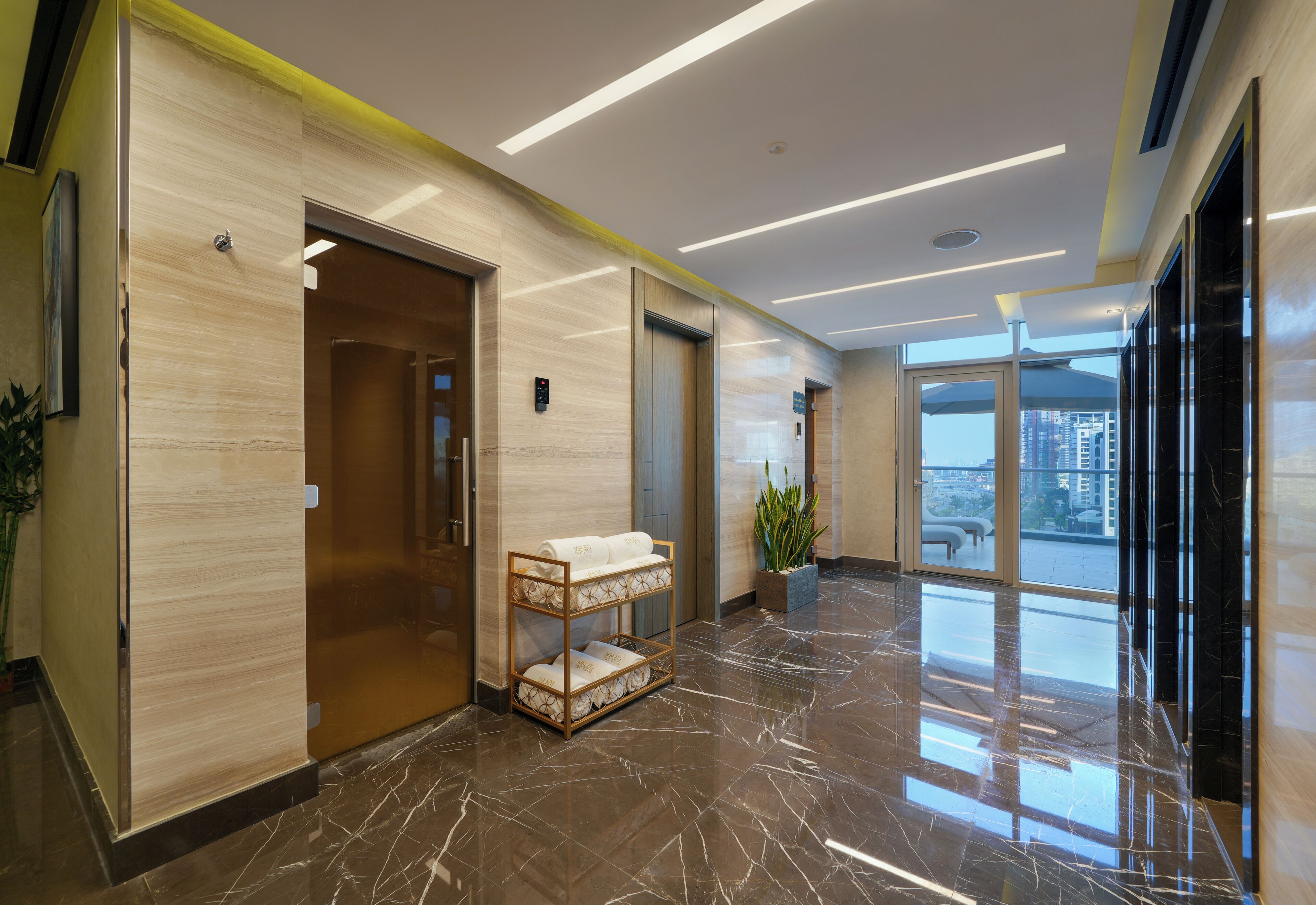 Un vestíbulo moderno con suelo de mármol, paneles de madera y una mesa de recepción.