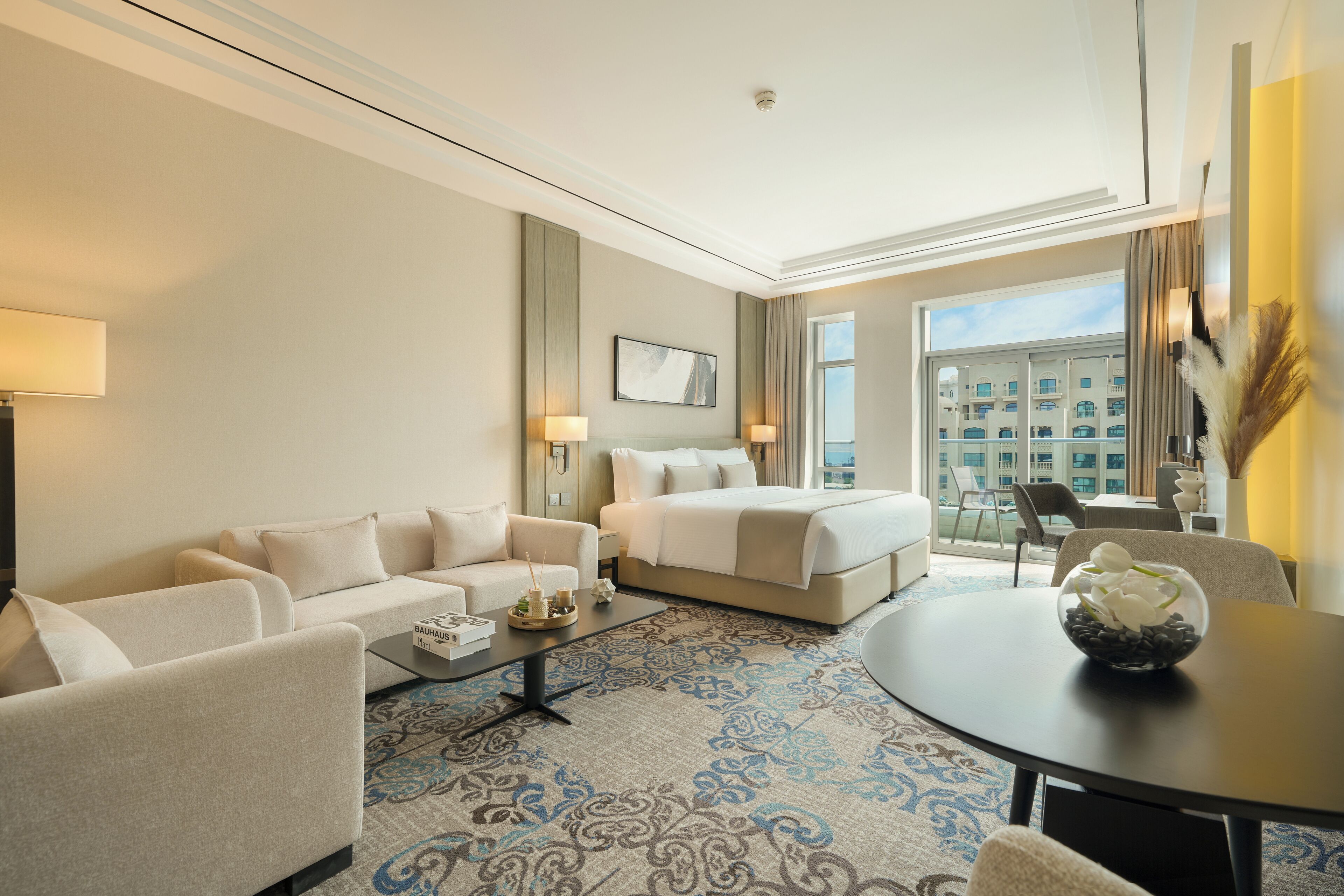 Une chambre d’hôtel avec un canapé, un lit, une table basse et une vue sur la ville.