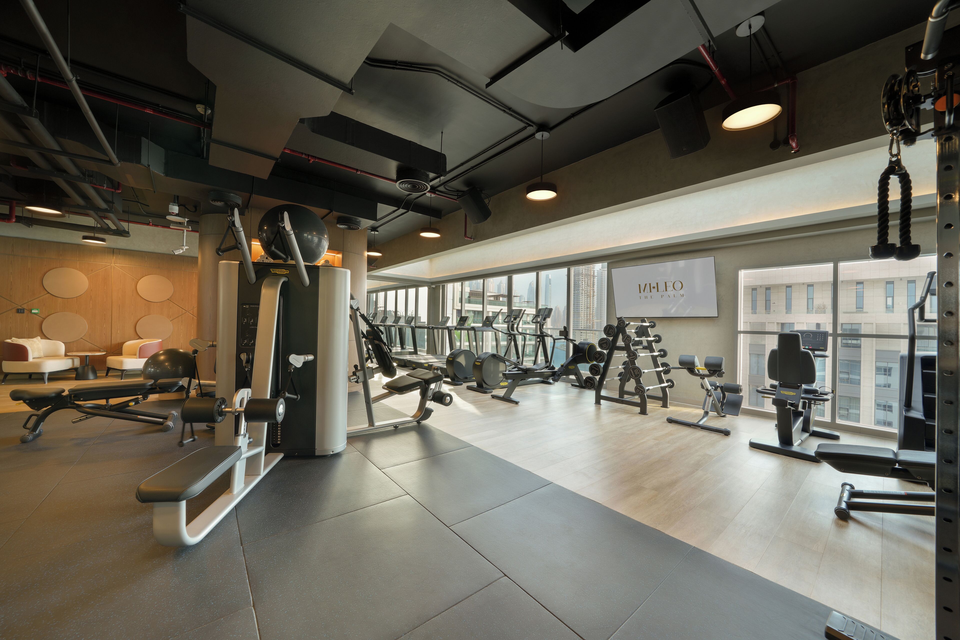 Un gimnasio moderno con diverso equipo de ejercicio, ventanas amplias y un diseño limpio y espacioso.