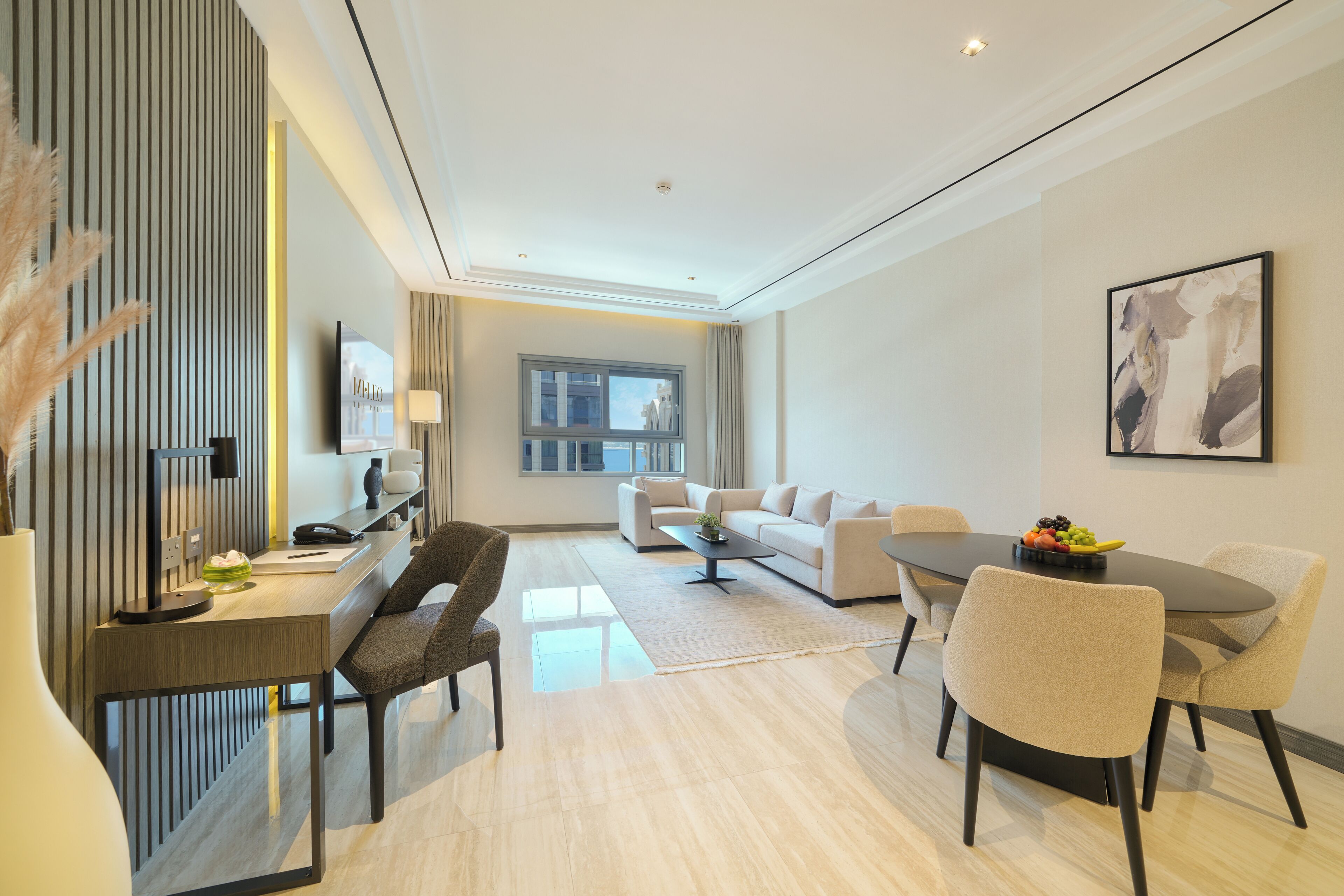 Een moderne hotelkamer met een bureau, bank, eettafel en stoelen.