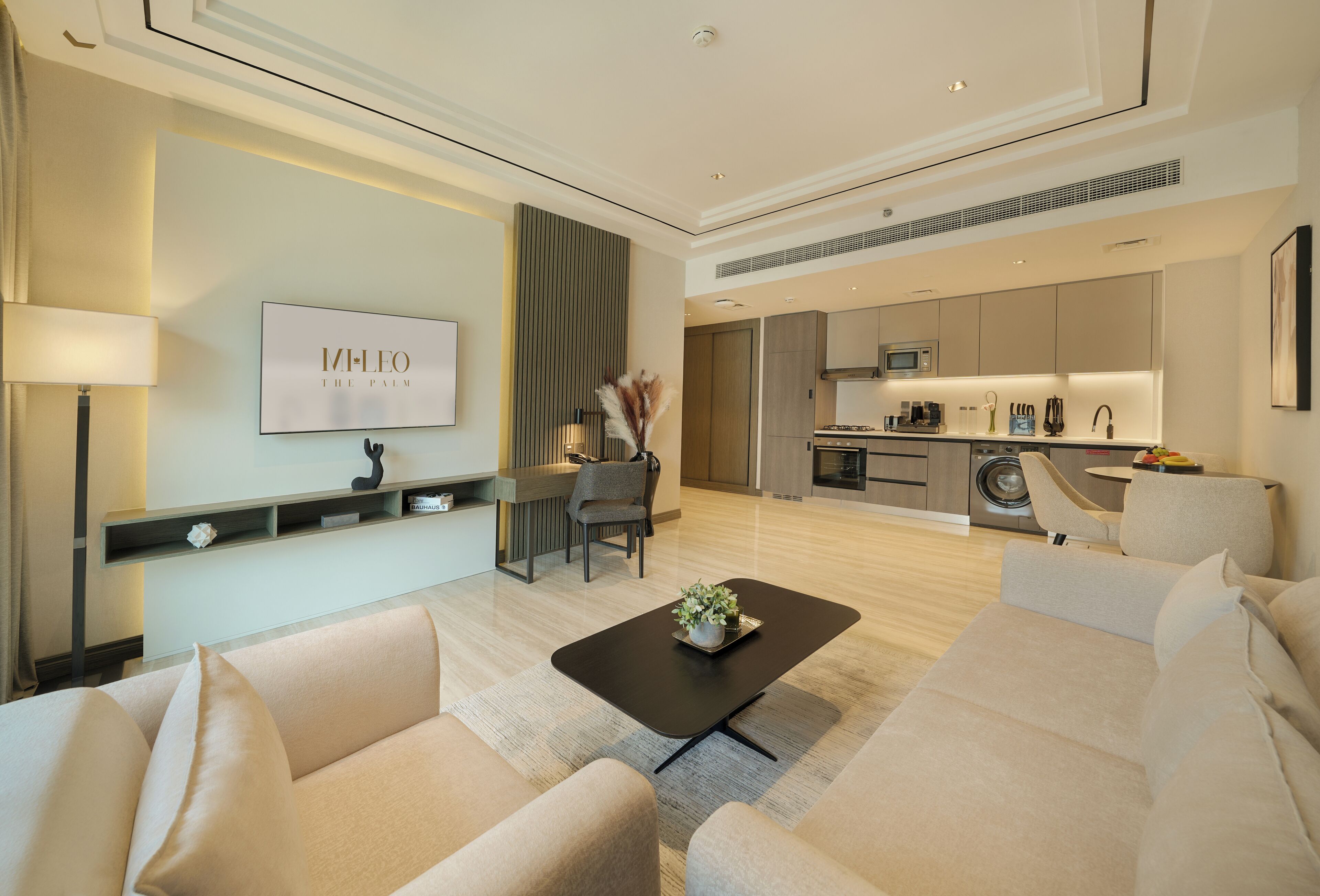 A modern living room with a sofa, a coffee table, and a TV mounted on the wall.