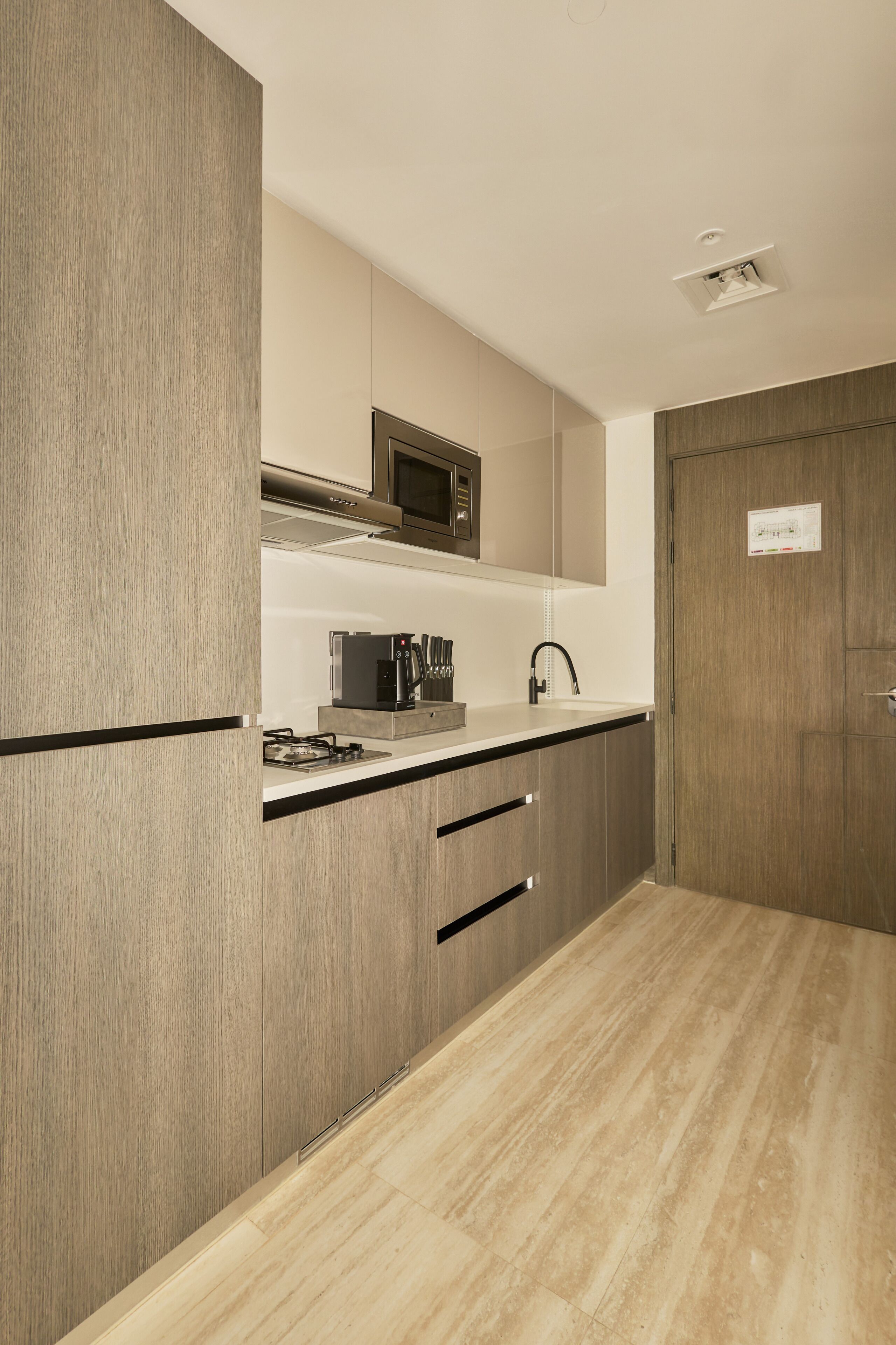 A modern kitchen with wooden cabinets, a stainless steel microwave, and a built-in coffee maker.