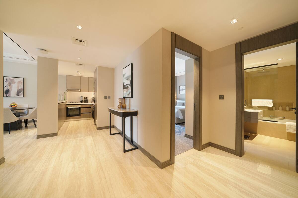 A modern hotel room with a kitchen, dining area, and bathroom.