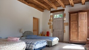 Un dormitorio con dos camas, un armario de madera y una pared de piedra.