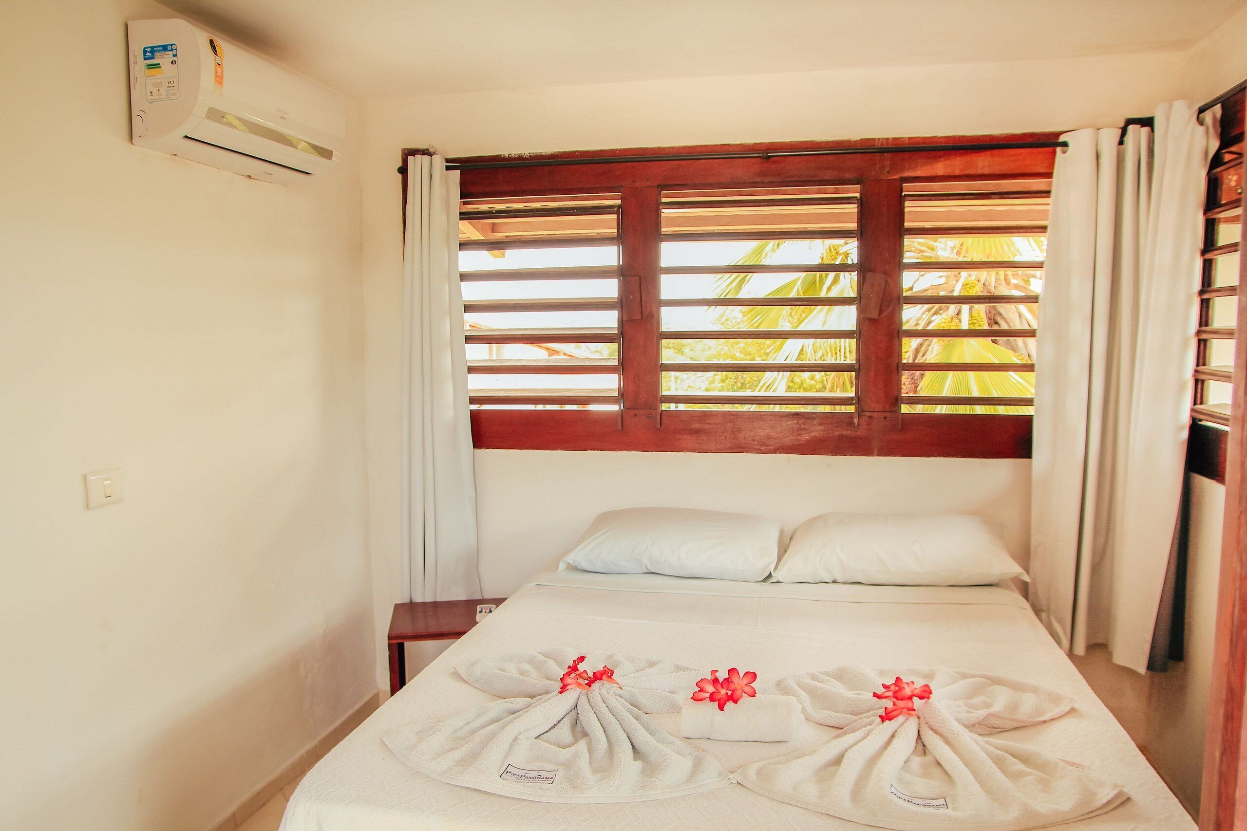 A single bed with a wooden headboard, white bedding, and towels arranged on the bed.