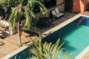 A swimming pool with a wooden deck, lounge chairs, and a palm tree. - Pipa Panorama Flats&Apartamentos (Tibau do Sul)