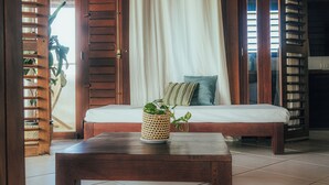 Una habitación con cama, una mesa de madera y una cesta de mimbre con una planta.
