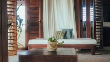 Um quarto com cama, uma mesa de madeira e uma cesta de vime com uma planta.