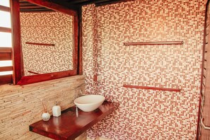 A bathroom with a tiled mosaic wall, a wooden bench, a sink with a mirror, and a towel rack. - Pipa Panorama Flats&Apartamentos (Tibau do Sul)