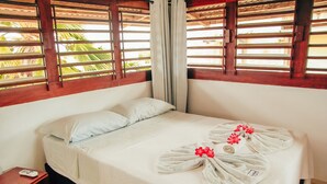 Una cama bien hecha con sábanas blancas y un arreglo de toallas con flores rojas.