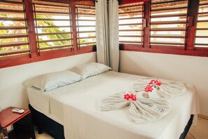 A neatly made bed with white linens and a towel arrangement featuring red flowers. - Pipa Panorama Flats&Apartamentos (Tibau do Sul)