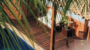 A wooden deck with potted plants and a chair. - Pipa Panorama Flats&Apartamentos (Tibau do Sul)