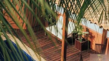 Um deck de madeira com plantas em vasos e uma cadeira.