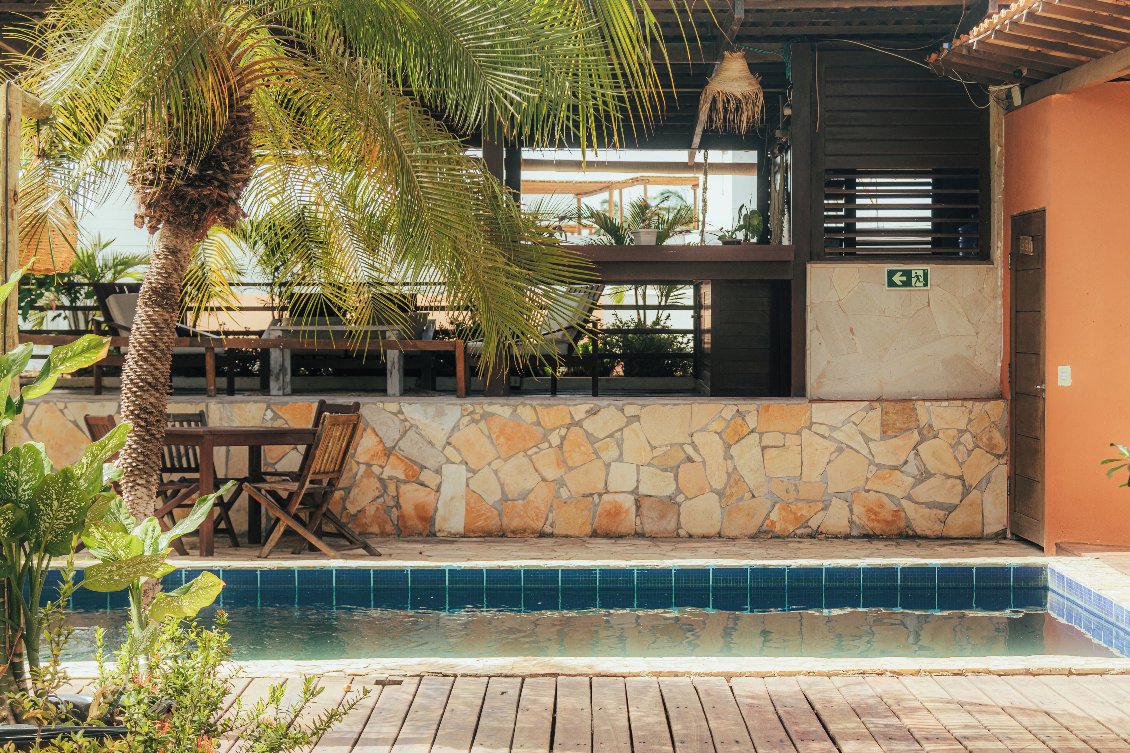 A poolside area with a stone wall, wooden deck, and outdoor seating.