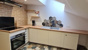 Een kleine keuken met een inbouwoven, een koffiezetapparaat en een spoelbak.
