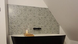 Een moderne badkamer met een vrijstaand bad, een wand met bloemenmotief en visgraat parketvloer.