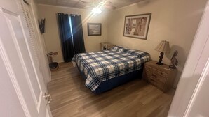 A bedroom with a bed, a nightstand, a lamp, a ceiling fan, and a framed picture on the wall. - OCHG Bel Harbour Unit 1 (Ocean City)