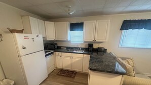 A compact kitchen with white cabinets, a microwave, a coffee maker, and a toaster. - OCHG Bel Harbour Unit 1 (Ocean City)