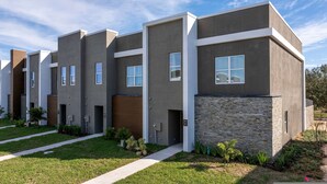 A modern multi-story residential building with a flat roof, large windows, and a stone facade. - Doppio Westside Haven Pool Disney Charm (Davenport)