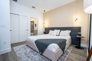 Un dormitorio moderno con una cama grande, mesitas de noche, una alfombra y una puerta.