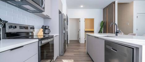 A modern kitchen with stainless steel appliances, a dishwasher, and a countertop with a sink.