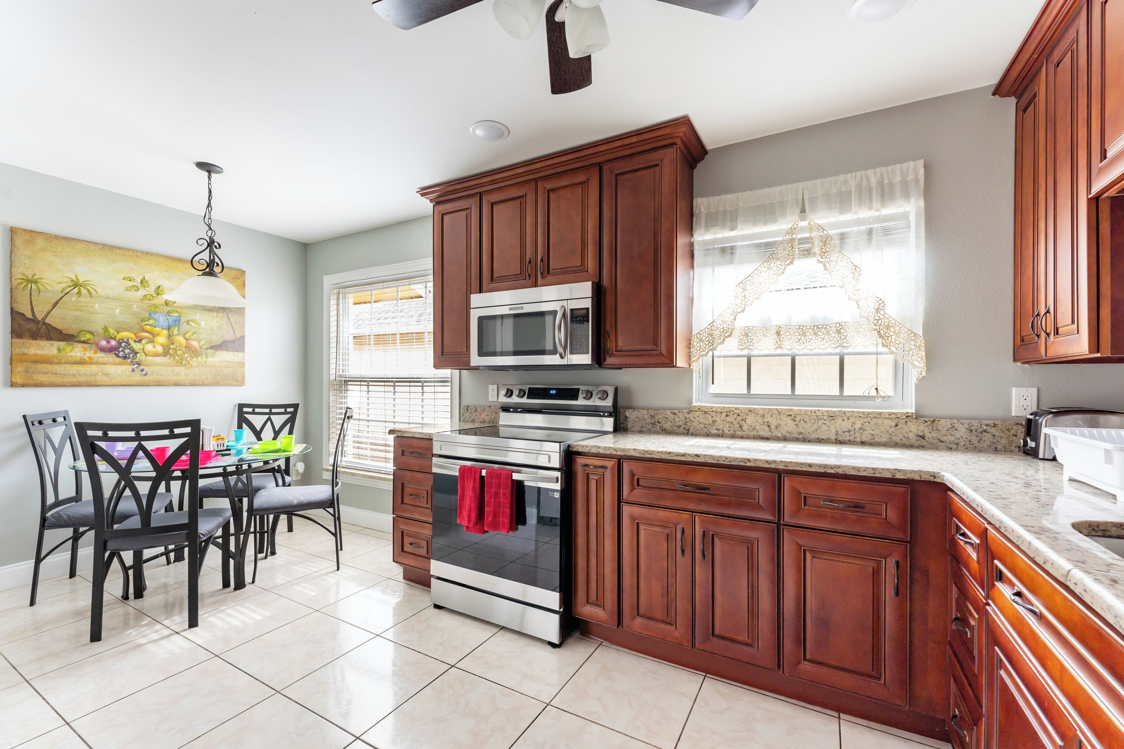 A kitchen with wooden cabinets, a stainless steel oven, and a dining area with chairs and a table.