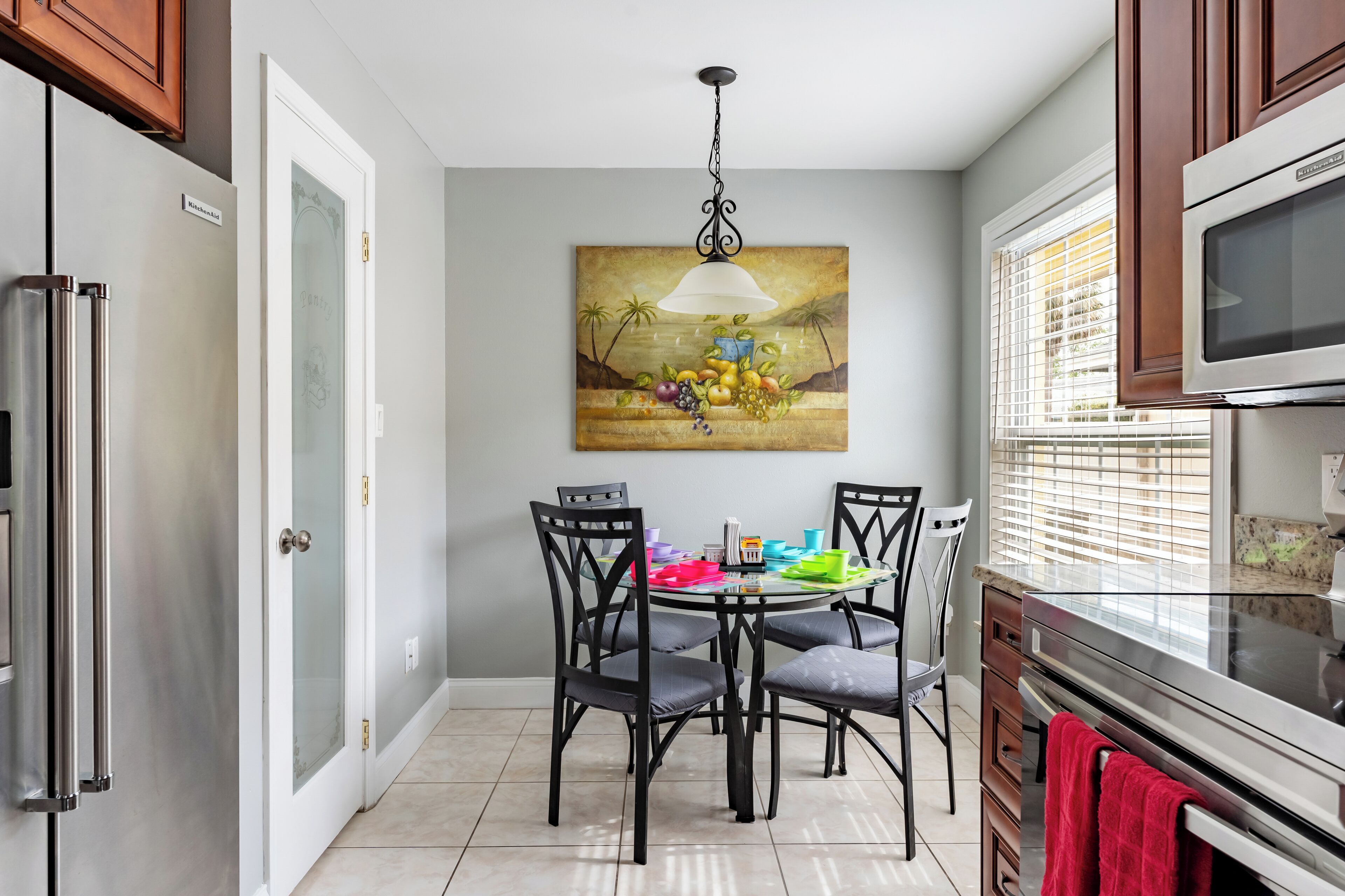 Une cuisine équipée d’une table à manger, de chaises, d’un réfrigérateur, d’un four à micro-ondes et d’un tableau accroché au mur.