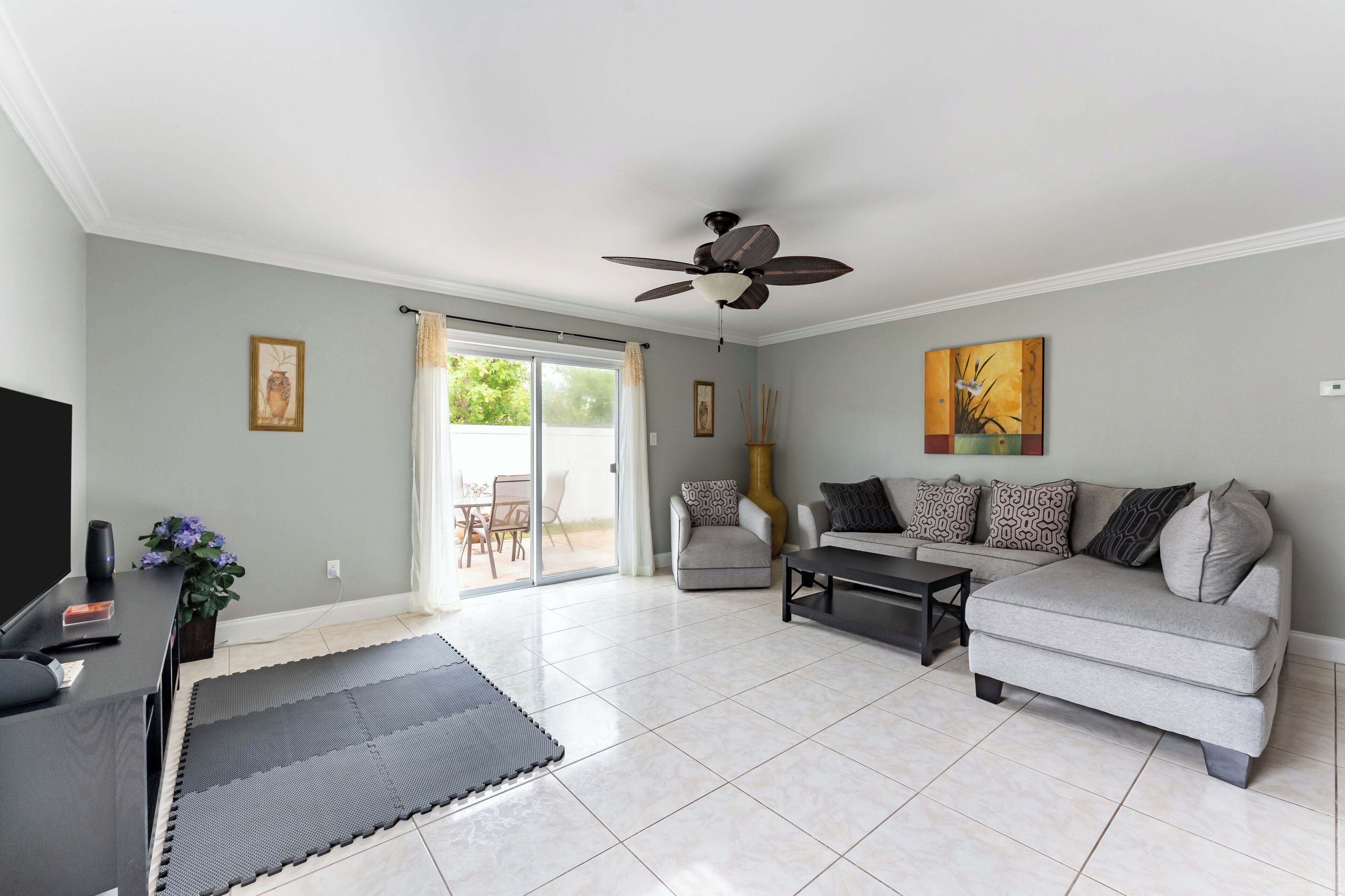 A living room with a grey sofa, a coffee table, a TV, and a ceiling fan.