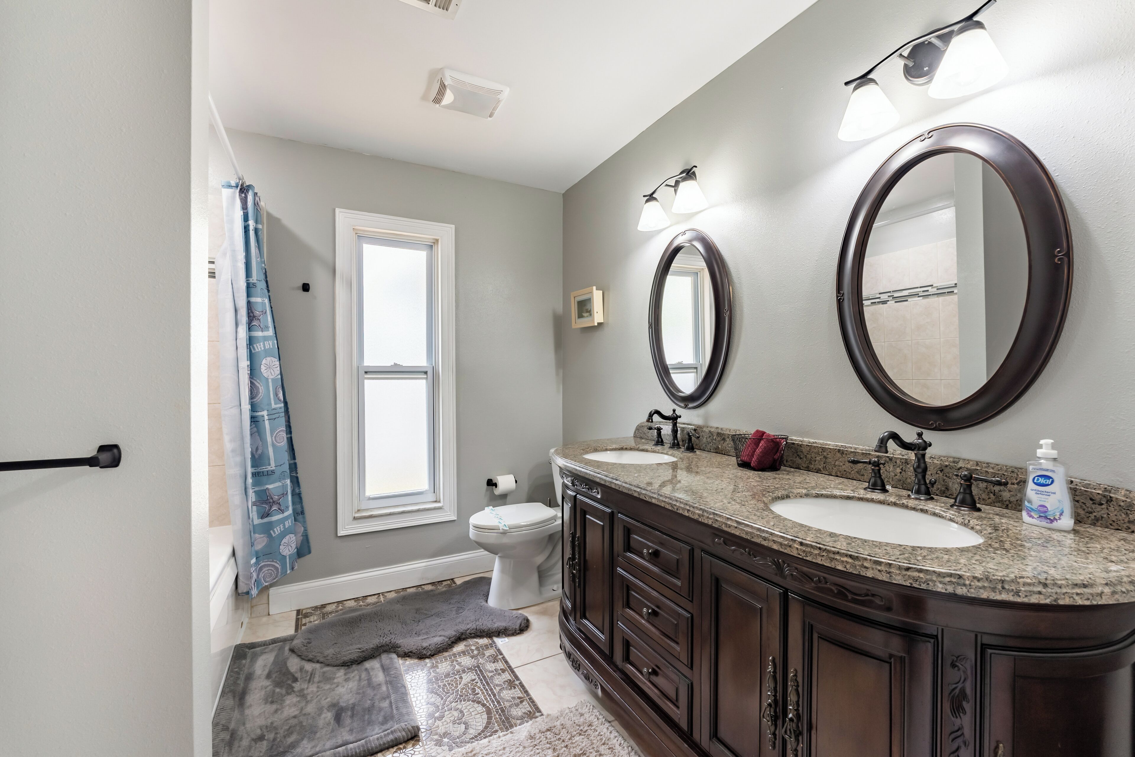 A bathroom with two sinks, a toilet, a shower, and a large mirror.