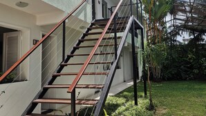 Una scala conduce a un balcone con vista su un giardino e palme.