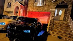 A black car parked in front of a brick building with a garage door. - Modern comfortable 3Beds 2Baths near EWR airport (Elizabeth)