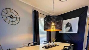 A dining area with a table, chairs, a hanging light fixture, a clock, and a framed picture on the wall. - Modern comfortable 3Beds 2Baths near EWR airport (Elizabeth)
