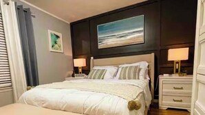 A bedroom with a bed, bedside tables, a bench, a painting, and a window with curtains. - Modern comfortable 3Beds 2Baths near EWR airport (Elizabeth)
