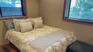 A bedroom with a bed, a bench, and a window with blinds. - Charming studio in awesome Idyllwild-Pine Cove with WiFi, AC (Idyllwild-Pine Cove)