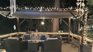 An outdoor deck with wicker furniture, string lights, and a pergola. - Charming studio in awesome Idyllwild-Pine Cove with WiFi, AC (Idyllwild-Pine Cove)