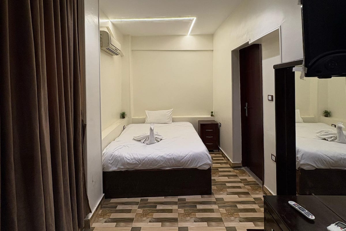 A hotel room with a bed, a dresser, a mirror, and a door.
