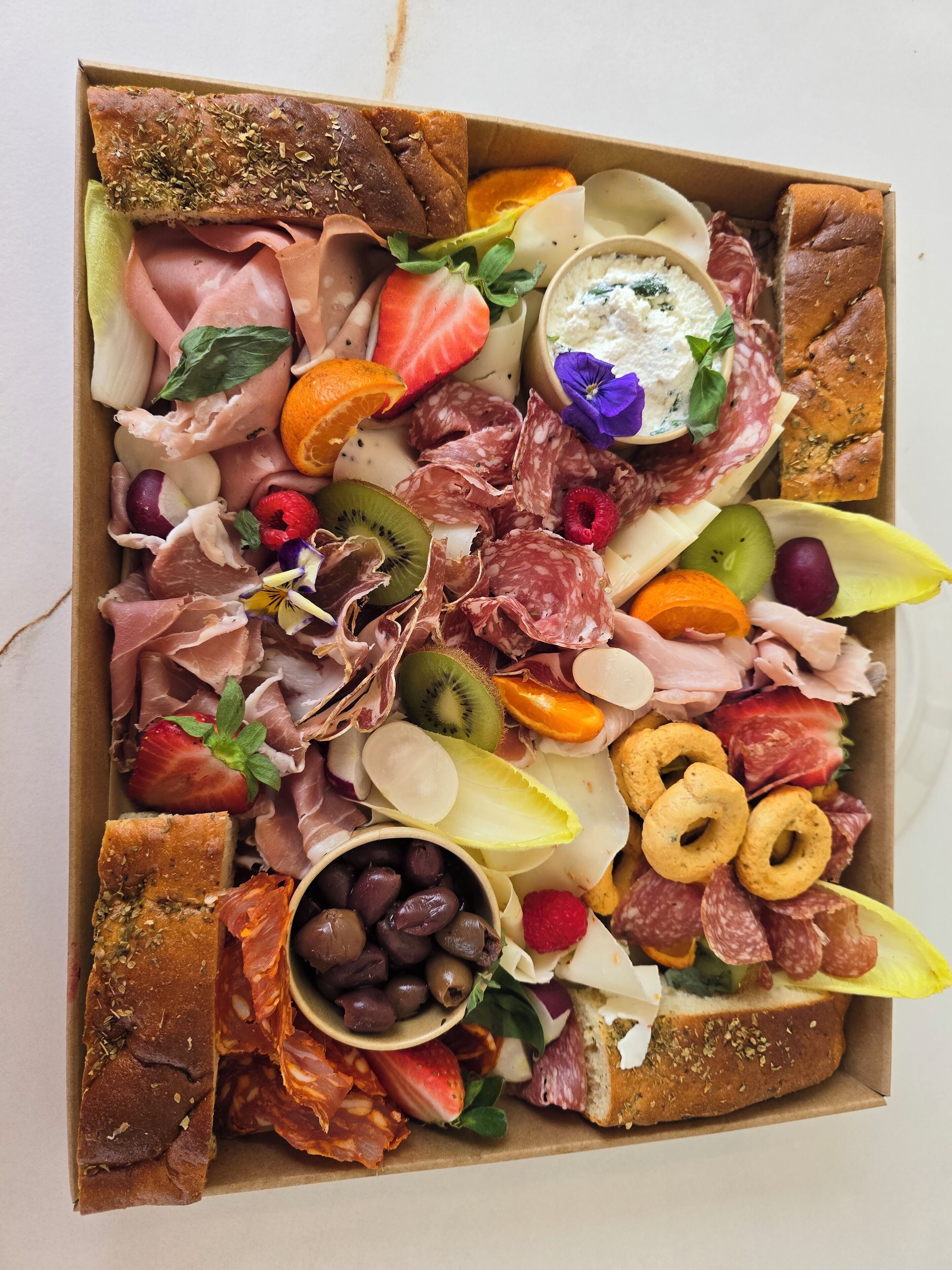 Eine Platte mit verschiedenen Wurstwaren, Käsesorten, Früchten und Crackern.