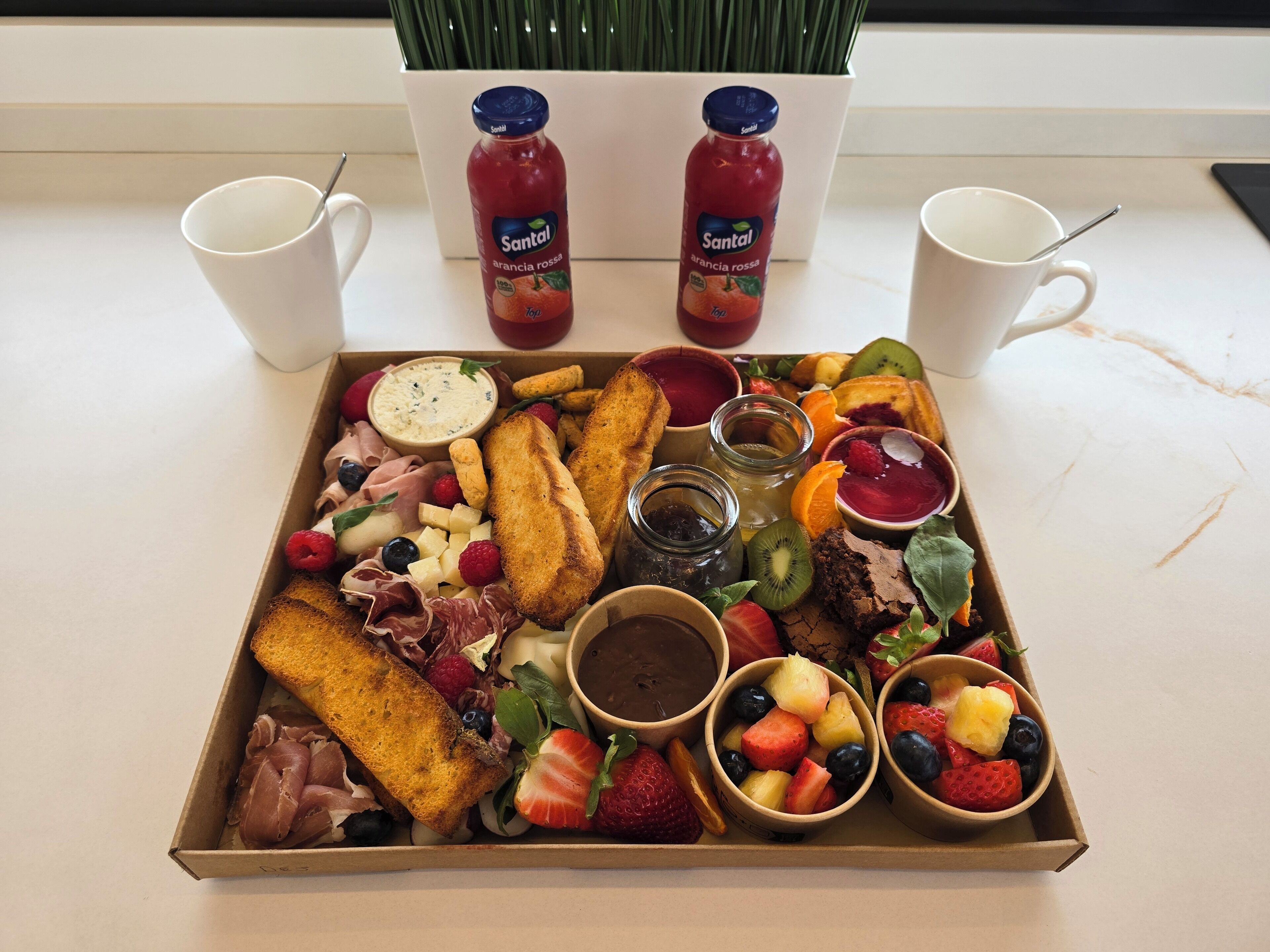 A breakfast tray with toast, fruit, cheese, and jam.