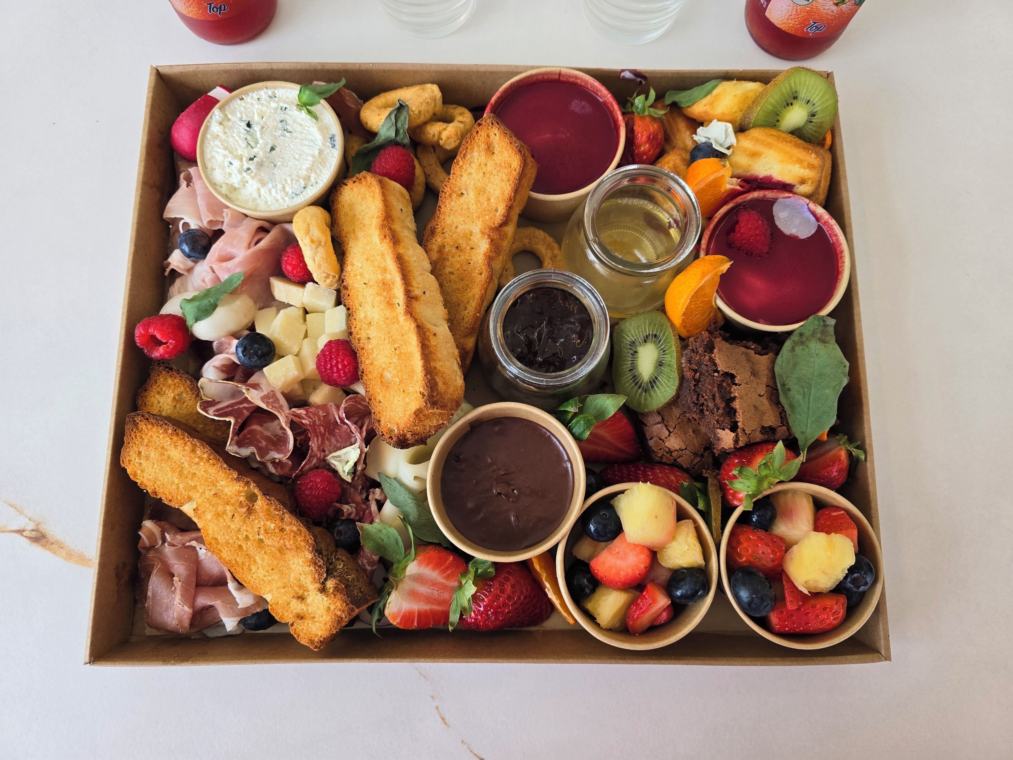 A charcuterie board with various meats, cheeses, fruits, and dips.