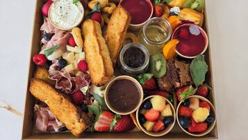 A charcuterie board with various meats, cheeses, fruits, and dips.