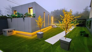 Une maison moderne avec une pelouse bien entretenue et un chemin menant à l’entrée.