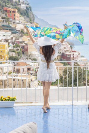 Un balcon offrant une vue sur des bâtiments aux couleurs vives et sur la mer.