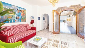 A living room with a red and white patterned sofa, a white coffee table, and a colorful painting on the wall. - YourHome - Villa Magnifica (Positano)